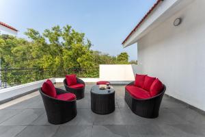 a patio with chairs and a table on a balcony at ELIVAAS Signature Casa Del Mundo With Pvt Pool, Bar, Lift & Scenic Hill Vistas in Vagator