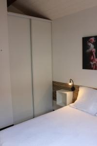 ein Schlafzimmer mit einem weißen Bett und einer Lampe in der Unterkunft La petite maison in Cuxac-Cabardès + 1 Foto