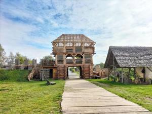 a wooden building with an archway in a field at Ferienhaus Sieroslaw polnische Ostsee mit Kamin in Sierosław