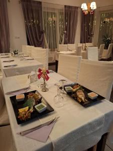 una sala da pranzo con tavoli bianchi con piatti di cibo di Vila Apuseni ad Arieşeni