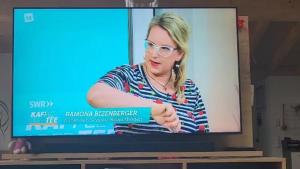 a tv screen with a woman holding a book at FEWO klein mit Garten in Feldberg +19 photos