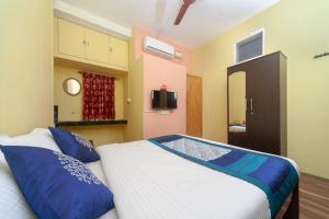 una camera da letto con un letto grande con cuscini blu di Hotel O B Square Homes a Singānallūr Altre 11 foto