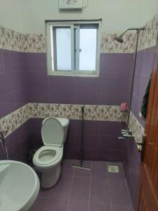 a bathroom with a toilet and a sink and a window at SerenityINn in Islamabad
