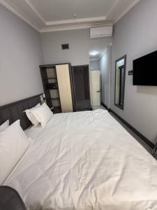 een groot wit bed in een kamer met een televisie bij Rauza Hotel Tashkent in Tasjkent +2 foto's
