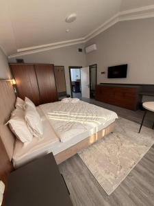 een slaapkamer met een groot bed en een flatscreen-tv bij Rauza Hotel Tashkent in Tasjkent