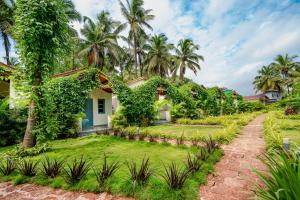 een huis met een tuin en palmbomen bij Aqua Bella Resort in Mandrem