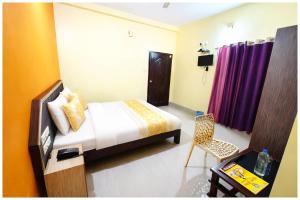 ein Schlafzimmer mit einem Bett und einem Stuhl in einem Zimmer in der Unterkunft Chakra Tirtha Road Hotel Premium D2 Stay Near Sea Beach - WiFi # Parking And Restaurant Facilities- Budget Hotel In Puri in Puri