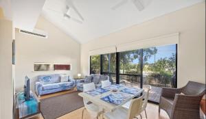 a living room with a table and chairs and a couch at Relaxing Beach shack at the Footprints complex in Preston Beach