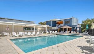 a swimming pool with chairs and a building at Relaxing Beach shack at the Footprints complex in Preston Beach