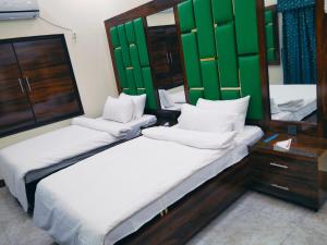 zwei Betten in einem Zimmer mit grünen Fensterläden in der Unterkunft Hotel Prime Residency in Karatschi