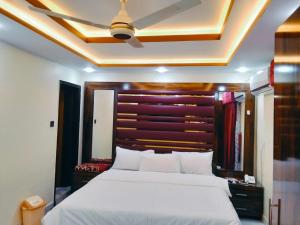 ein Schlafzimmer mit einem großen Bett mit einem hölzernen Kopfteil in der Unterkunft Hotel Prime Residency in Karatschi