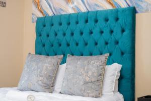 a blue headboard with two pillows on a bed at Chic Alberton in Alberton