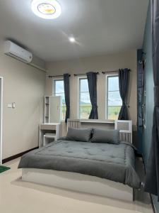a bedroom with a large bed and two windows at บ้านไร่สกายดาว in Pak Chong
