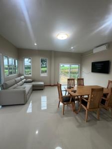 a living room with a table and chairs and a couch at บ้านไร่สกายดาว in Pak Chong