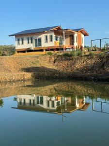 a house on a hill next to a body of water at บ้านไร่สกายดาว in Pak Chong