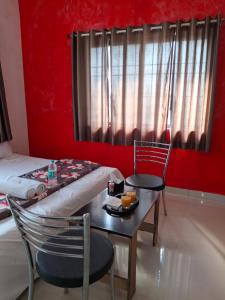 Zimmer mit einem Tisch, 2 Stühlen und einem Bett in der Unterkunft Vrindavan Hotel and Restaurant in Malavli