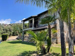a stone house with palm trees in front of it at Villa Laura in Coccorino