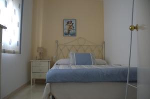 a bedroom with a bed with blue sheets and a dresser at Casa 3 min andando playa AC WiFi 8 pax Doñana in Matalascañas
