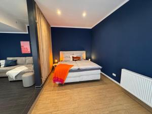 a bedroom with blue walls and a bed with an orange blanket at Ferienwohnung Erfurter Seen - Nöda 2 in Nöda