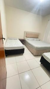 two beds in a room with white tile floors at Descanso e aconchego in Aparecida