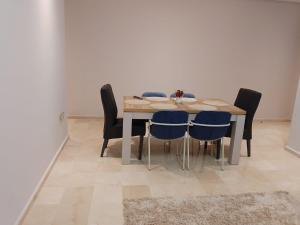 a dining room table with blue chairs and a white wall at Les belles loges in Bouskoura +28 photos