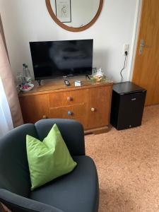 a living room with a chair and a television on a dresser at Room!Moor in Schwarzenbach an der Saale