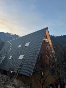 een gebouw met een metalen dak waarop zonnepanelen zijn aangebracht bij Mysa, A-frame cottage in Shirir