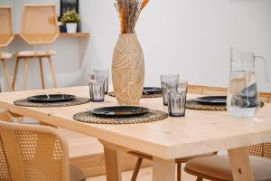 a wooden table with plates and a vase on it at Portside Residence Piräus in Piraeus