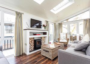 a living room with a fireplace and a tv at Woodside Bay Lodge Retreat in Wootton Bridge