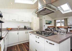 a kitchen with white cabinets and a stove top oven at Woodside Bay Lodge Retreat in Wootton Bridge