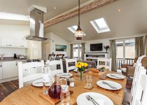 a kitchen and dining room with a wooden table and chairs at Woodside Bay Lodge Retreat in Wootton Bridge +5 photos