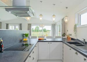 eine Küche mit weißen Schränken und einer Spüle in der Unterkunft Aspen Lodge Escape in Hengrave