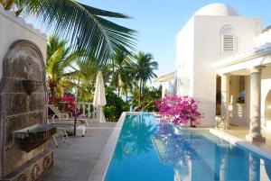 a swimming pool next to a villa with palm trees at Casablanca Escape in La Majahua