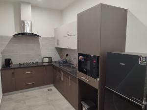 a kitchen with brown cabinets and a black refrigerator at Sky Park Nest in Islamabad