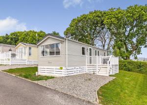 a small white house on a gravel road at Meadow Lakes Holiday Park in St Austell +32 photos