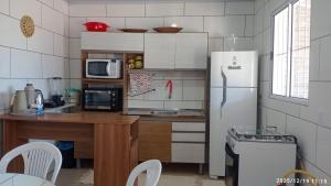 a kitchen with a refrigerator and a table with chairs at Casa da Praia Capão da Canoa in Capão da Canoa