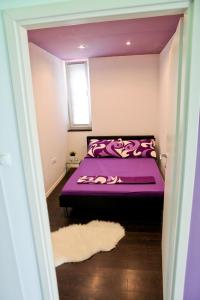 fioletowe łóżko w pokoju z oknem w obiekcie Apartmani Fila Varaždin w mieście Varaždin