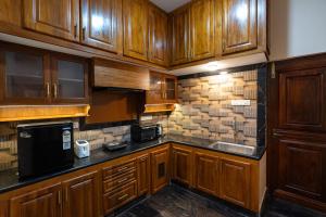 a kitchen with wooden cabinets and a black microwave at SK Grand Palace in Pondicherry