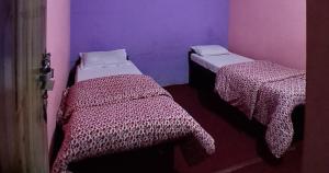 two beds in a room with purple and purple walls at Kimche Guest House in Astam