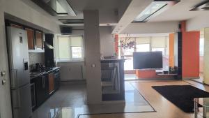 a kitchen with an open floor plan with a tv at Apartament modern 3 camere ultracentral McDonalds Orange in Craiova