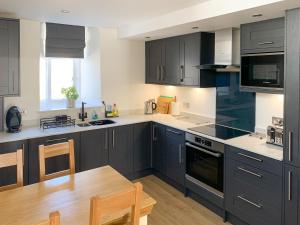 een keuken met donkerblauwe kasten en een houten tafel bij The Chapel in Staveley