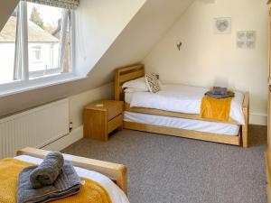een zolderslaapkamer met twee bedden en een raam bij The Chapel in Staveley +7 foto's