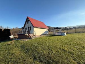 een witte schuur met een rood dak in een veld bij Spacerowy Zakątek in Ślemień