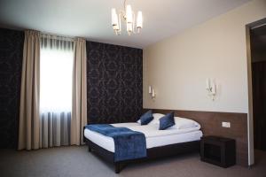 a bedroom with a bed with a blue blanket and a window at Hotel Cztery Pory Roku in Bielsk Podlaski