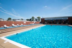 a large swimming pool with chairs and a building at Suntrail House in Great Clacton