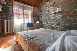 una camera da letto con un letto e un muro di pietra di Loutra Mountain Nature a Aridaía