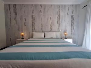 een slaapkamer met een groot bed met blauwe en witte strepen bij Refugio Madeira in Caniço