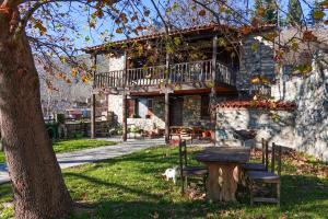 una casa con un albero e una panchina di fronte ad essa di Loutra Mountain Nature a Aridaía