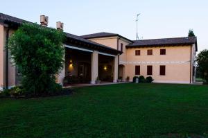 une grande maison avec une pelouse verte en face de celle-ci dans l'établissement Agriturismo alle Rose, à Ca Baglioni