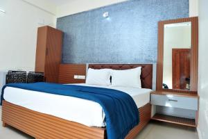 een slaapkamer met een groot bed met een blauwe muur bij Alfa Tourist Home, Batheri in Sultan Bathery